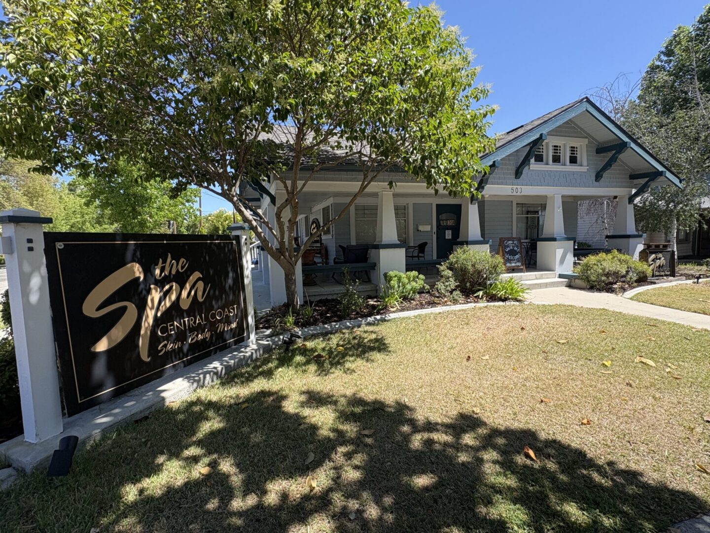 Spa bungalow with porch, sign, and lawn